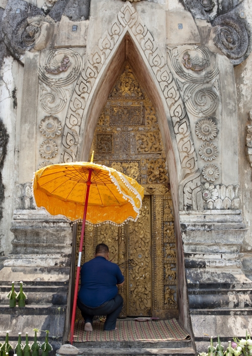 Man praying in front of a stupa in hang, Savannakhet, Laos