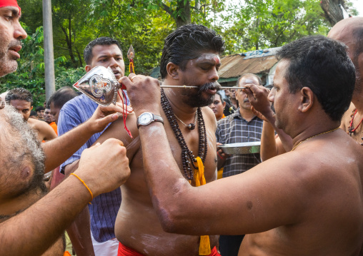 A Devotee Cheek Is Pierced With A Giant Skewer By A Priest At Thaipusam Hindu Festival At Batu Caves, Southeast Asia, Kuala Lumpur, Malaysia