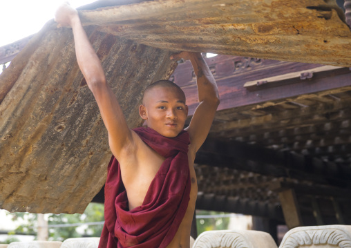 Novice Monk In Nat Taung Kyaung Monastery Carrying Furniture, Bagan, Myanmar