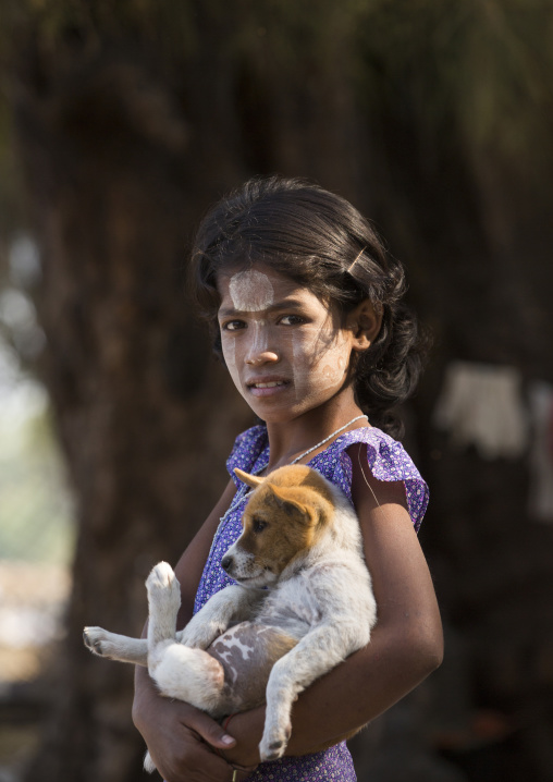 Girl With Thanaka On Cheeks Carrying A Dog, Ngapali, Myanmar