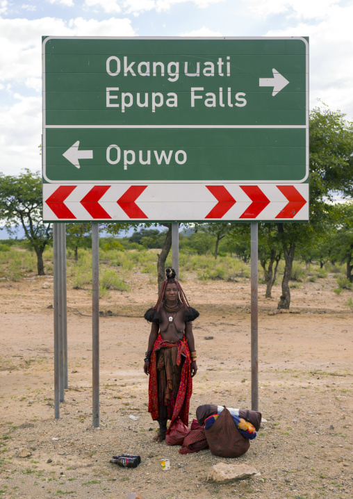 Himba Woman Standing Under A Road Sign, Epupa, Namibia