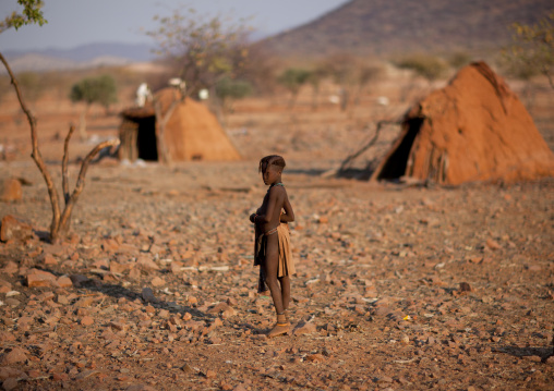 Himba Girl In Front Of Two Huts, Okapale Area, Namibia