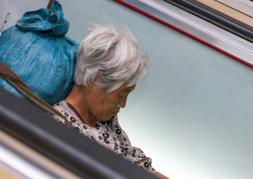 Tired North Korean woman resting on escalators stairs inside subway station, Pyongan Province, Pyongyang, North Korea