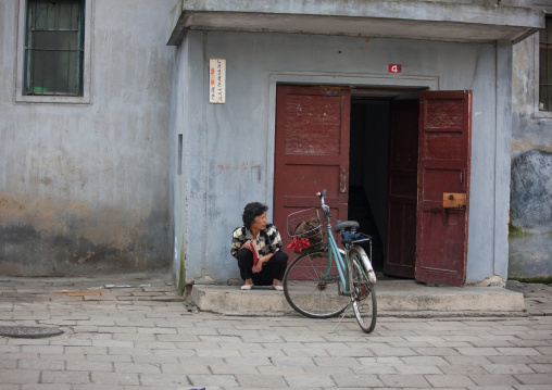 North Korean woman sit at the entrance of a building, Pyongan Province, Pyongyang, North Korea