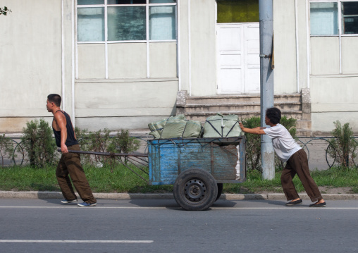 North Korean people pushing a heavy cart in the street, Pyongan Province, Pyongyang, North Korea