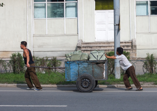 North Korean people pushing a heavy cart in the street, Pyongan Province, Pyongyang, North Korea