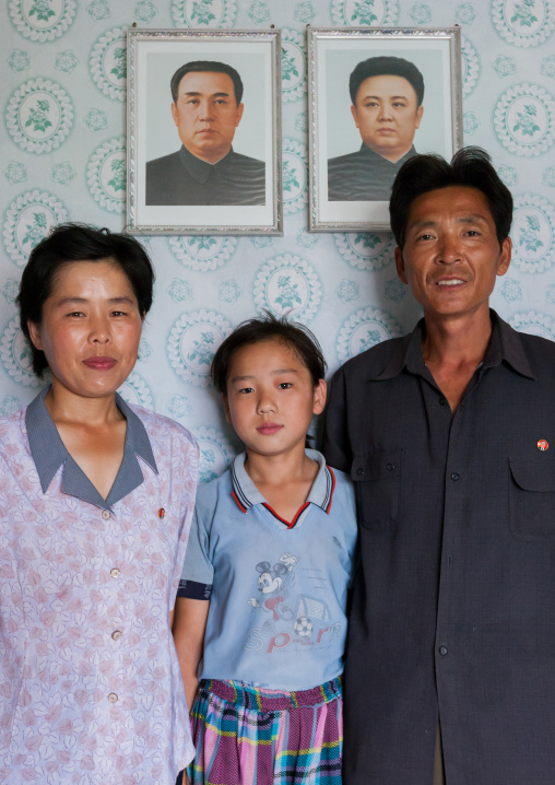 North Korean family in front of the portraits of the Dear Leaders inside their house, Kangwon Province, Chonsam Cooperative Farm, North Korea