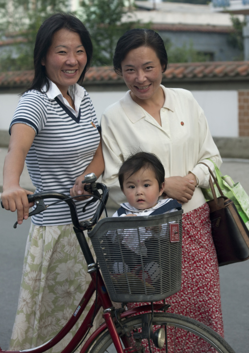 Smiling North Korean women with a baby in a bicycle basket, North Hwanghae Province, Sariwon, North Korea