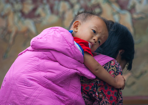 North Korean woman carrying a skinny boy on her back, North Hwanghae Province, Sariwon, North Korea