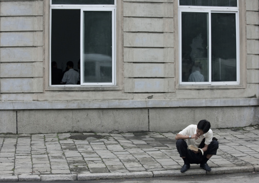 North Korean man reading a book in the street, Pyongan Province, Pyongyang, North Korea