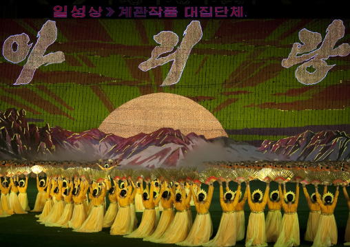 Dancers women in choson-ot in front of a giant sun on mount Paektu made by human pixels holding up colored boards during Arirang mass games, Pyongan Province, Pyongyang, North Korea