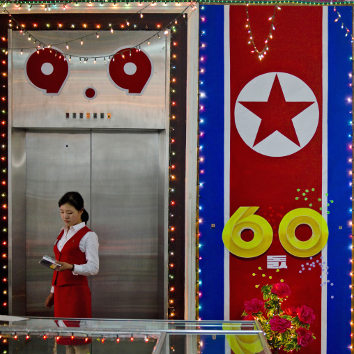 North Korean woman saleswoman in a clothes shop decorated for the 60th anniversary of the regim, Pyongan Province, Pyongyang, North Korea