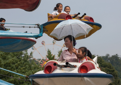 North Korean people having fun on a flying saucer attraction in Taesongsan funfair, Pyongan Province, Pyongyang, North Korea