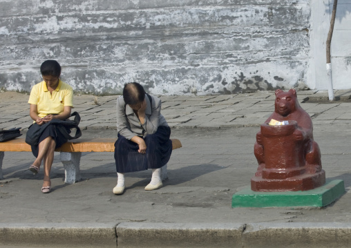 North Korean women sit on a bench near a trash bin, Pyongan Province, Pyongyang, North Korea
