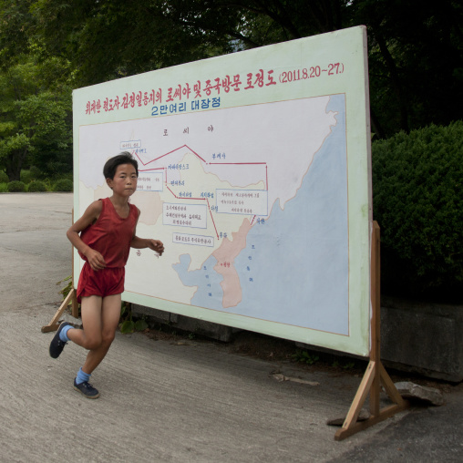 Young boy running in front of Kim Jong il last train trip map, South Hamgyong Province, Hamhung, North Korea