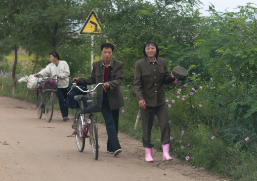 North Korean couple walking alongside the road with a bicycle in the countryside, North Hamgyong Province, Jung Pyong Ri, North Korea