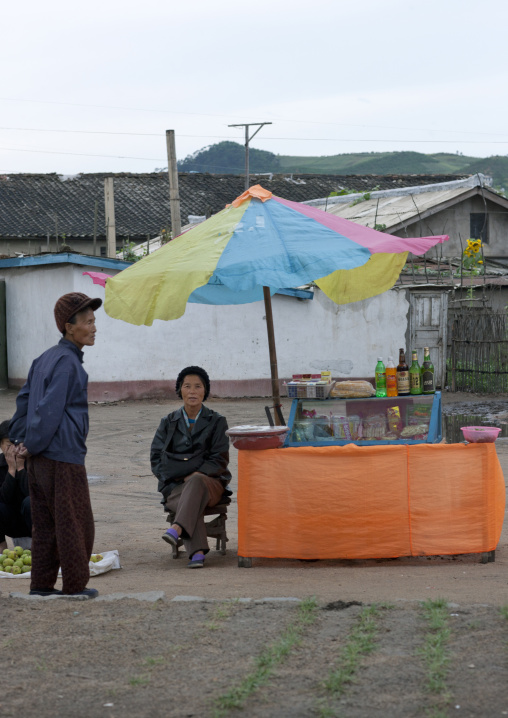Food and drinks street vendor sitting under umbrella, North Hamgyong Province, Jung Pyong Ri, North Korea