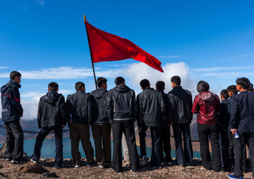 Group of students with red flag in front of lake at mount Paektu, Ryanggang Province, Mount Paektu, North Korea