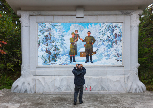 Foreign tourist taking a picture of a propaganda fresco depicting Kim il song as a child with his parents, Ryanggang Province, Samjiyon, North Korea