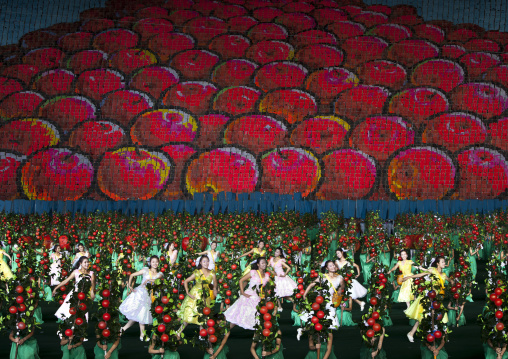 Women dancing in front of apples made by children pixels holding up colored boards during Arirang mass games in may day stadium, Pyongan Province, Pyongyang, North Korea