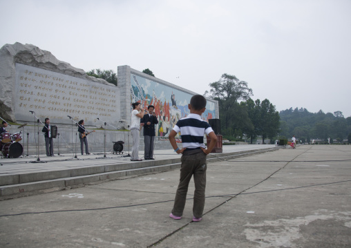 North Korean boy listening to a band playing music on national day in the street, Pyongan Province, Pyongyang, North Korea