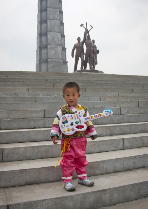 North Korean boy with a toy guitar on the stairs of the Juche tower built to commemorate Kim il-sung's 70th birthday, Pyongan Province, Pyongyang, North Korea
