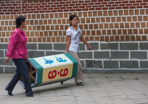 North Korean women carrying a propaganda billboard in the street, North Hwanghae Province, Kaesong, North Korea