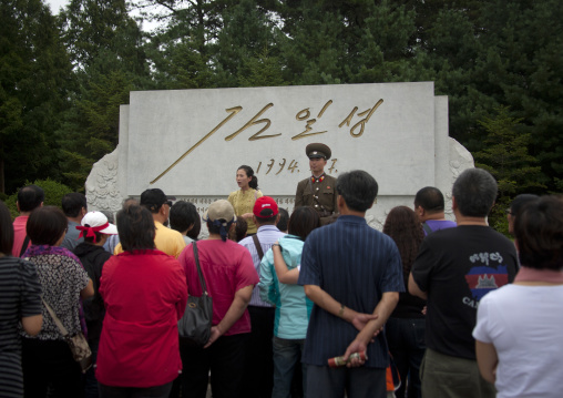 North Korean tour guide with a group of tourists in front of a monument with the signature of Kim il Sung, North Hwanghae Province, Panmunjom, North Korea