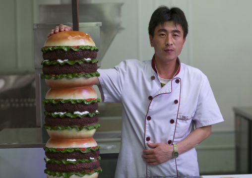 North Korean cook with a giant hamburger in a fast food restaurant, Pyongan Province, Pyongyang, North Korea