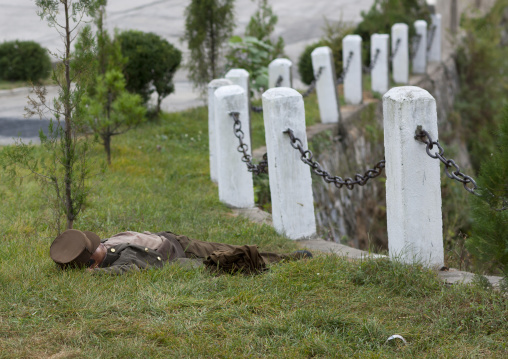 North Korean soldier resting in the grass alongside a country road, Kangwon Province, Wonsan, North Korea