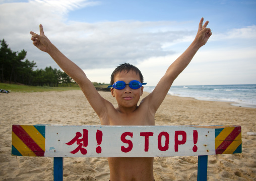 North Korean boy on a beach in front of stop sign, North Hamgyong Province, Chilbo Sea, North Korea