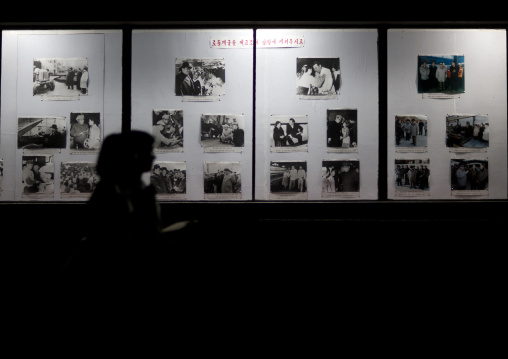 North Korean women passing at night in front of a billboard depicting the life of Kim il Sung, Pyongan Province, Pyongyang, North Korea