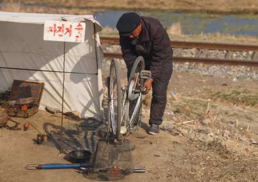 North Korean man repairing a bicycle, South Pyongan Province, Nampo, North Korea