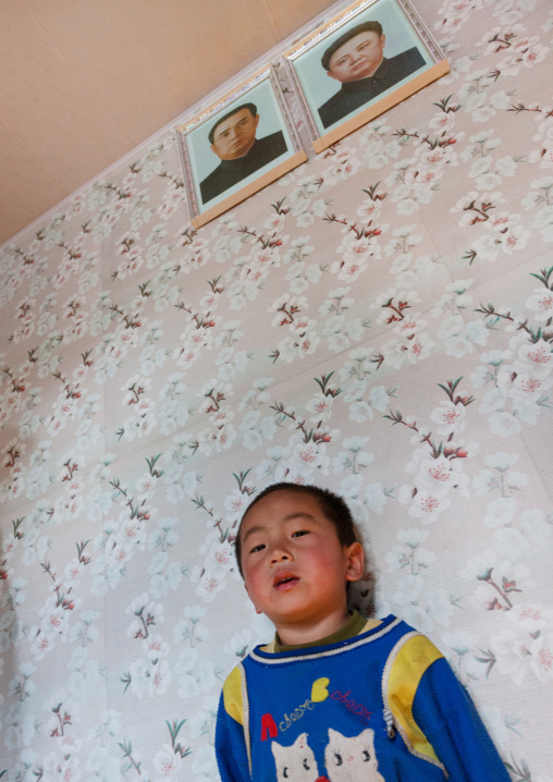 North Korea boy below the official portraits of the Dear Leaders, Kangwon Province, Chonsam Cooperative Farm, North Korea