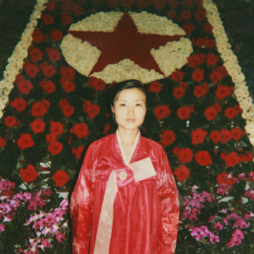 Polaroid of a woman posing in front of a red star made of Kimjongilia flowers during the international Kimilsungia and Kimjongilia festival, Pyongan Province, Pyongyang, North Korea