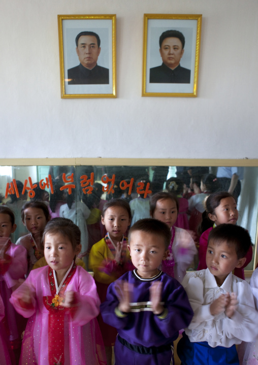 North Korean children in a primary school below the portraits of the Dear Leaders, South Pyongan Province, Chongsan-ri Cooperative Farm, North Korea