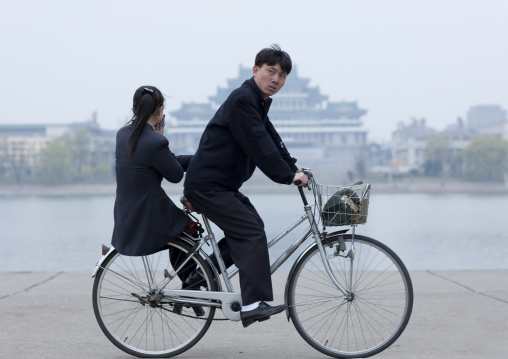 North Korean couple riding a bicycle on Kim il Sung square, Pyongan Province, Pyongyang, North Korea