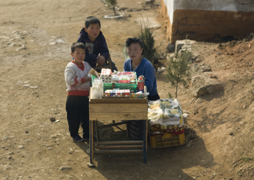 North Korean woman with her children selling food and cigarettes along the road in the countryside, South Pyongan Province, Nampo, North Korea