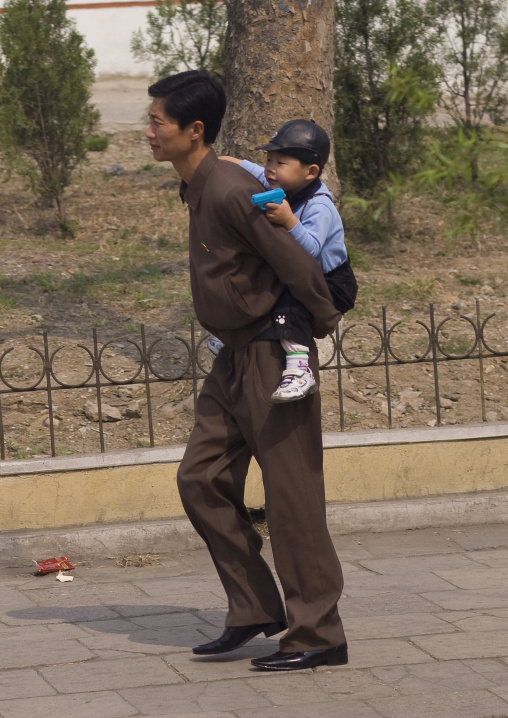 North Korean father walking in the street with his son on his back, Pyongan Province, Pyongyang, North Korea