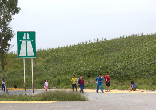 North Korean children playing in front of a highway entrance road sign near the Demilitarized Zone, North Hwanghae Province, Panmunjom, North Korea
