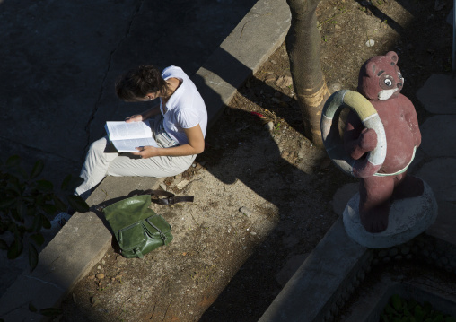 North Korean student reading a book on a bench in the sun, Kangwon Province, Wonsan, North Korea