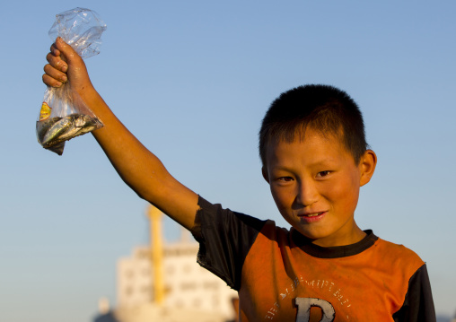 North Korean child boy showing fishes in a plastic bag he catched, Kangwon Province, Wonsan, North Korea