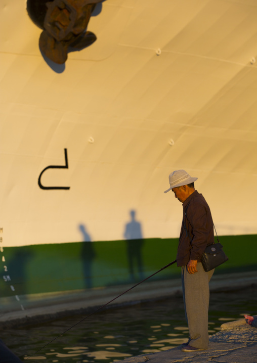North Korean senior man fishing in the sea in front of a ship, Kangwon Province, Wonsan, North Korea