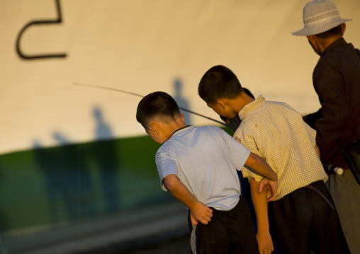 North Korean children fishing in the sea in front of a ship, Kangwon Province, Wonsan, North Korea