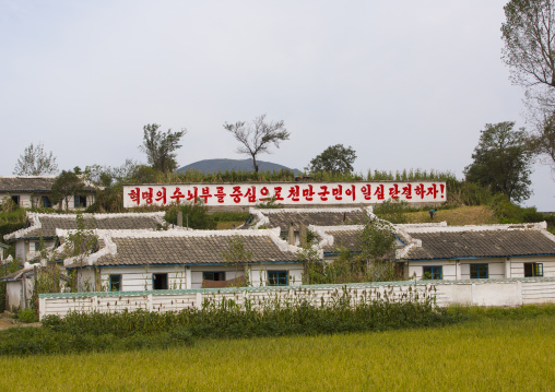 North Korean propaganda billboard in front of houses in a village, South Hamgyong Province, Hamhung, North Korea