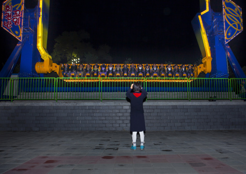 North Korean girl taking a picture of a fairground attraction in Kaeson youth park, Pyongan Province, Pyongyang, North Korea