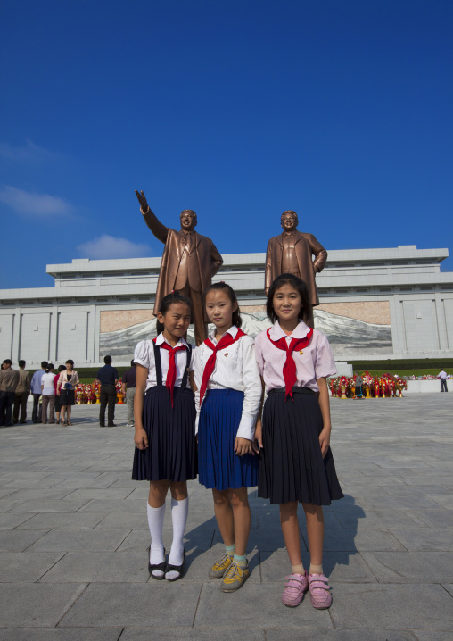 North Korean pioneers girls in front of the two statues of the Dear Leaders in the Grand monument on Mansu hill, Pyongan Province, Pyongyang, North Korea