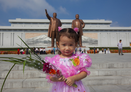 North Korean girl with flowers paying respect to the two statues of the Dear Leaders in Grand monument of Mansu hill, Pyongan Province, Pyongyang, North Korea