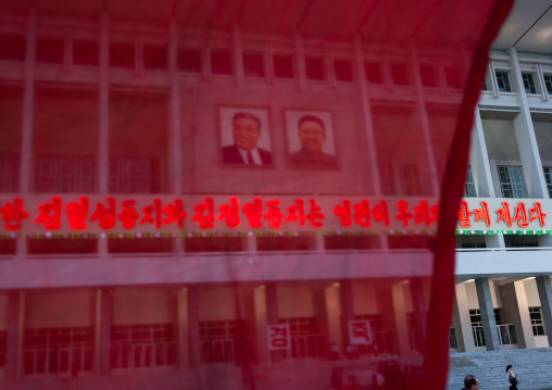 Red flag in front of the official portraits of the Dear Leaders on a building, Pyongan Province, Pyongyang, North Korea