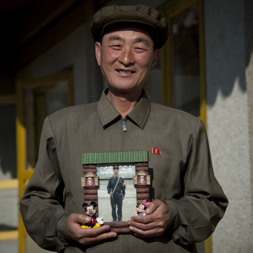 North Korean man showing his son picture serving in the army in a Mickey mouse frame, North Hamgyong Province, Jung Pyong Ri, North Korea